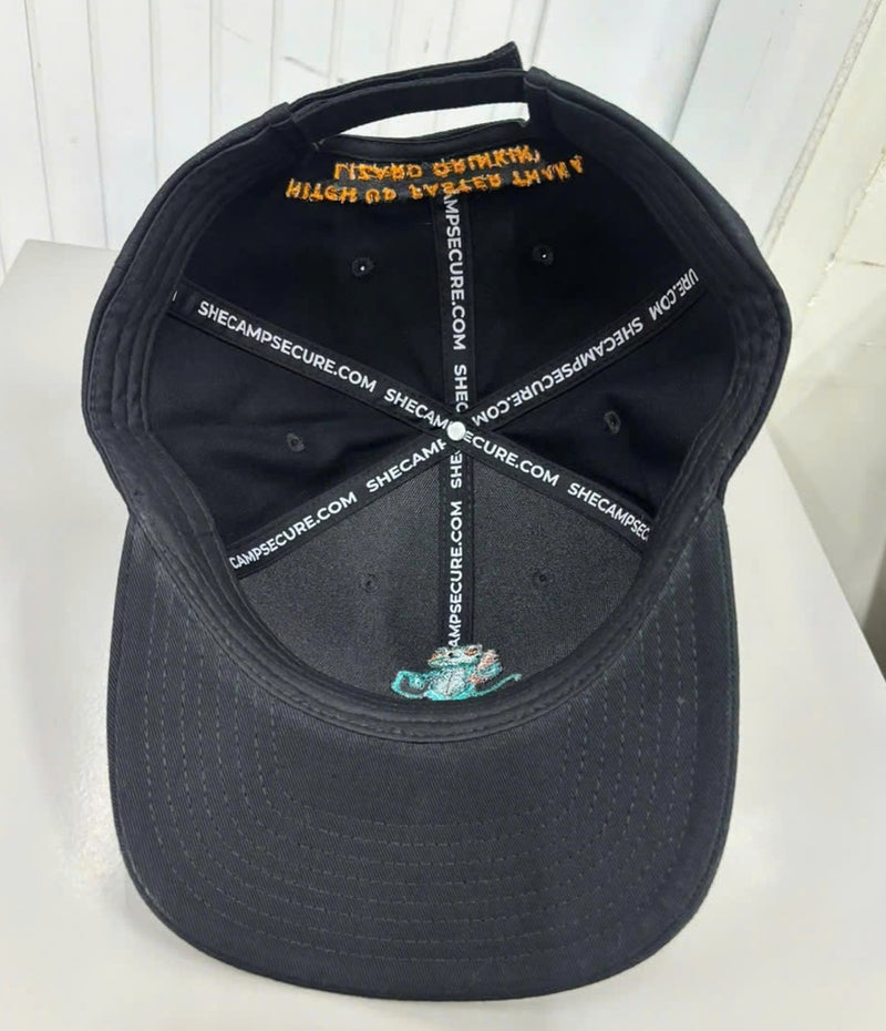 Pretow Mate™ Interior view looking into the black baseball cap. The internal seams are covered with custom white branding tape reading "SHECAMPSECURE.COM". The underside of the embroidered front gecko logo and the mirrored stitch work of the orange rear slogan are visible against the black panels.